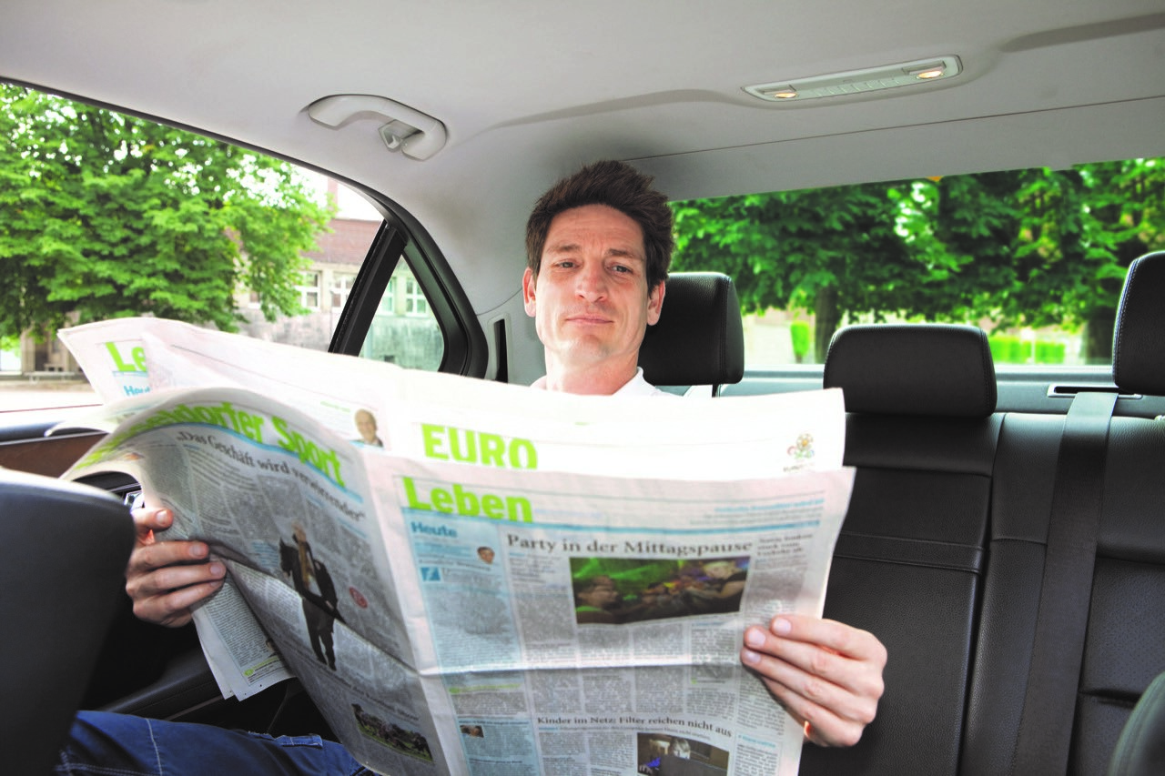 Fahrgast liest Zeitung im Taxi